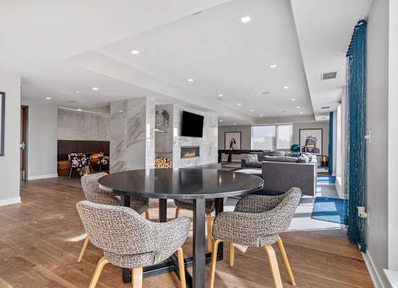 A modern dining room with a black table and grey chairs.