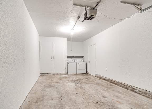 A white wall with a washing machine in the middle.