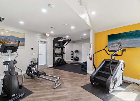 A gym with a yellow wall and a painting of a mountain scene.