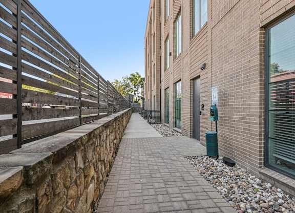 A walkway with a stone wall on one side and a metal fence on the other.