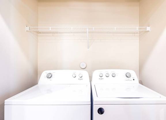 Two white washing machines in a small laundry room.