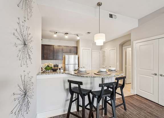 A modern kitchen with a dining table set for two.