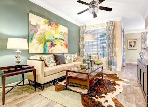 A living room with a couch, a coffee table, and a painting on the wall.