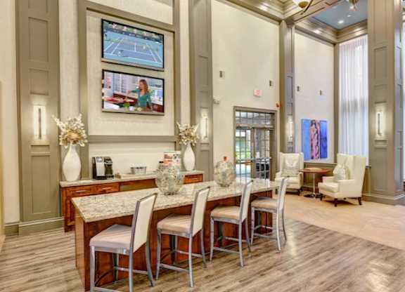 A dining room with a table set for four and a television mounted on the wall.