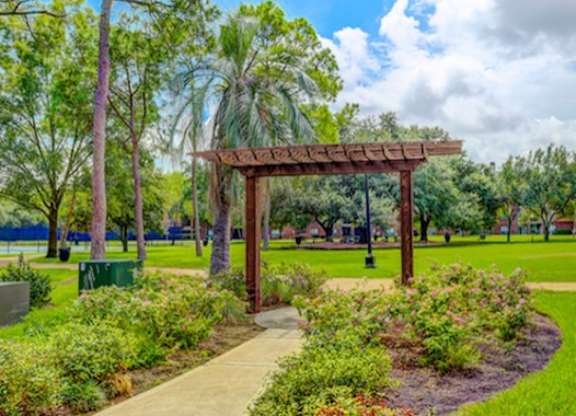 A park with a wooden pergola and a pathway.