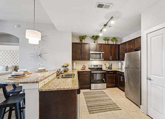 A kitchen with a refrigerator, sink, and oven.