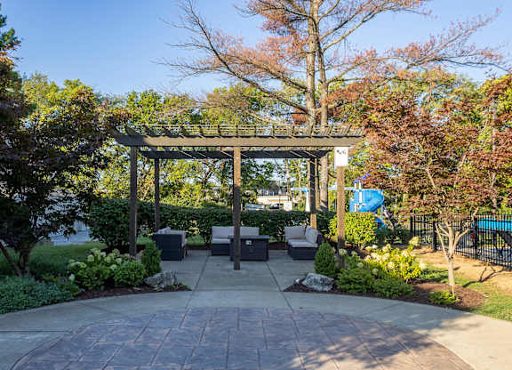 A gazebo is surrounded by trees and bushes in a park.