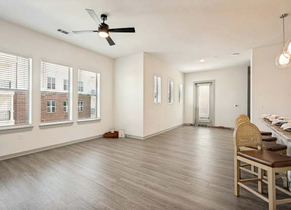 A room with a ceiling fan and a dining table with chairs.