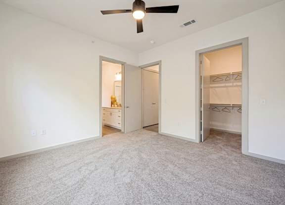 A room with a ceiling fan and carpeted floor.