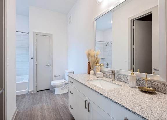A bathroom with a toilet, sink, and mirror.