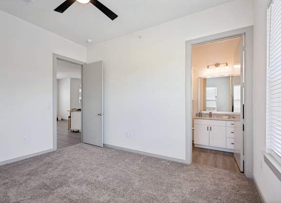 A room with a ceiling fan and a bathroom visible through an open door.