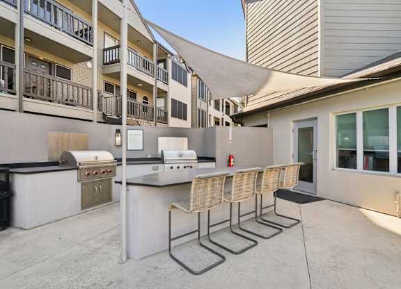 A patio with a barbecue grill and chairs.