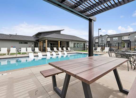 A wooden table is in the foreground of a pool area.