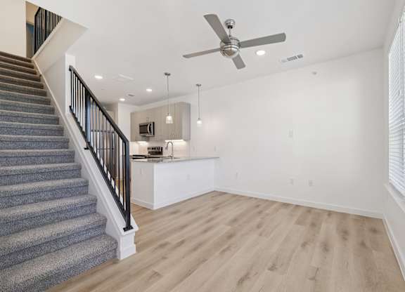 A spacious room with a staircase and a ceiling fan.
