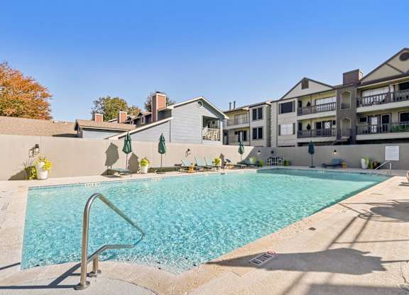 A swimming pool in front of a building with a clear blue sky.