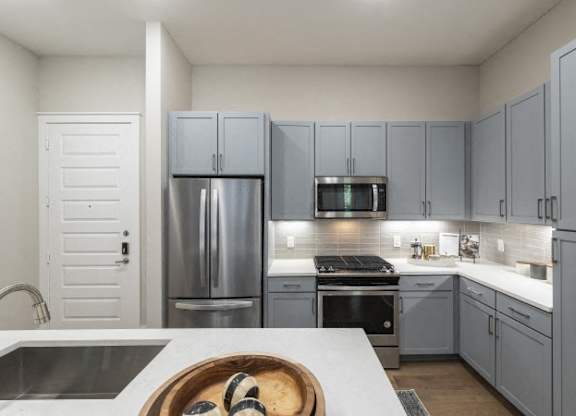 A modern kitchen with a white countertop and grey cabinets.