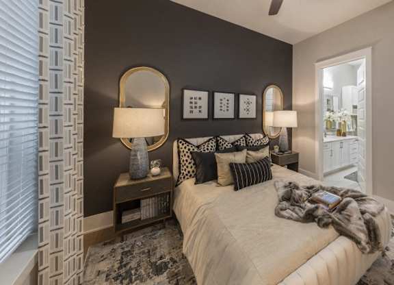 A bedroom with a bed, two lamps, and a mirror on the wall.