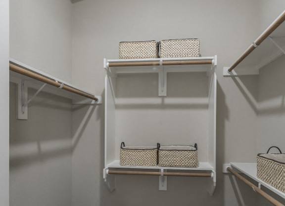 A white closet with three shelves and baskets on them.