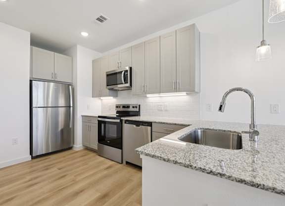 A kitchen with a granite countertop and stainless steel appliances.