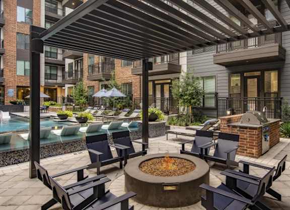 A patio with a fire pit and chairs.