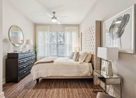 A bedroom with a bed, dresser, and a ceiling fan.
