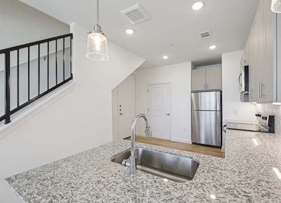 A kitchen with a granite countertop and a stainless steel sink.