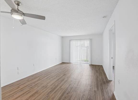 A room with a ceiling fan and wooden flooring.