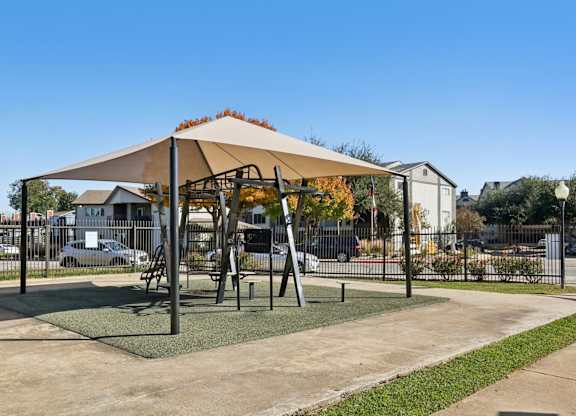 A playground with a swing set and a canopy.