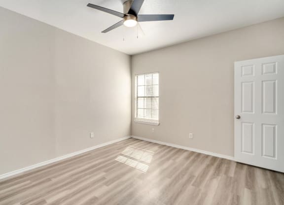 an empty living room with a ceiling fan and a window