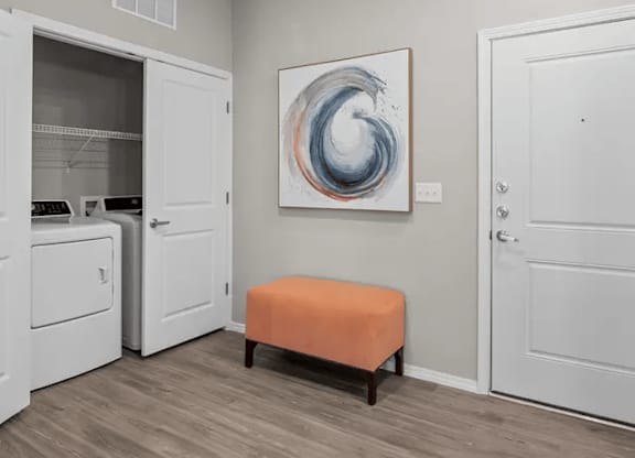 A room with a white door, a white cabinet, a white washing machine, a white fridge, a white wall, a white light switch, a white light, a white floor, a white ceiling, a white painting, a white