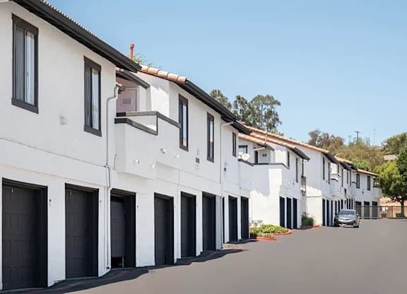 A row of white houses with black garage doors.
