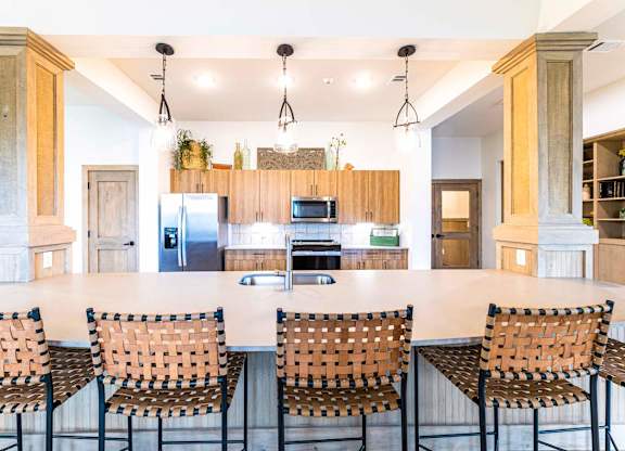 A kitchen with a white table and chairs and a refrigerator in the background.