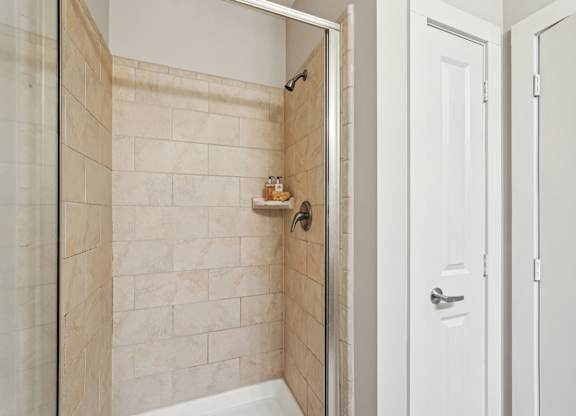 A white door is open to a bathroom with a tiled shower.