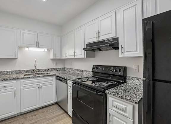 A kitchen with black appliances and white cabinets.
