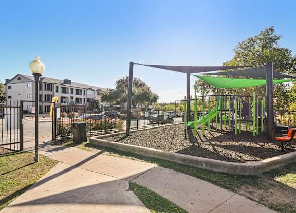A playground with a green slide and a red bench.