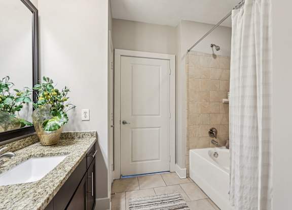 A bathroom with a white door, a white tub, and a white shower curtain.