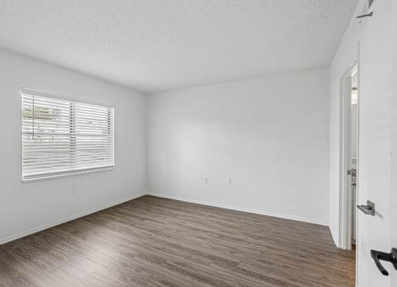 A room with a door and a window with blinds.