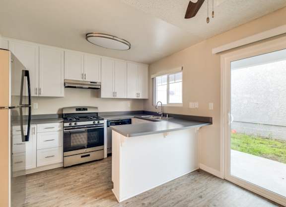 A kitchen with white cabinets and a black fridge.