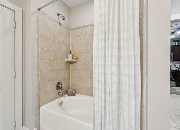A white bathroom with a tub, shower, and a white door.