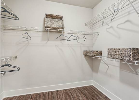 A white closet with a wooden floor and a white door.