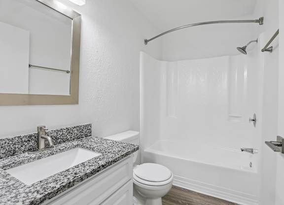 A bathroom with a marble countertop and white fixtures.