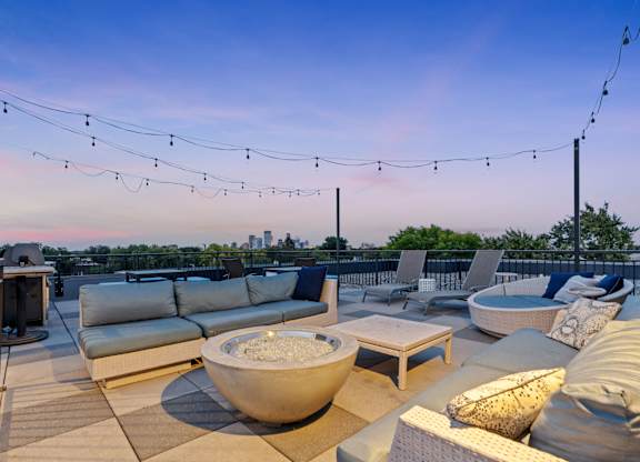 a roof deck with couches and chairs and a fire pit