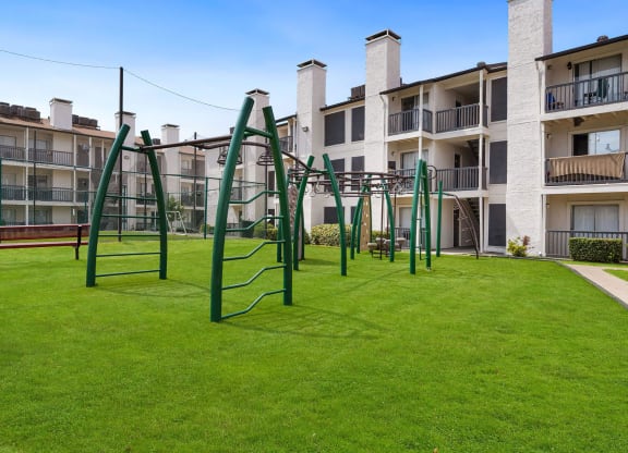 a playground with a monkey bars swing set in front of an apartment building