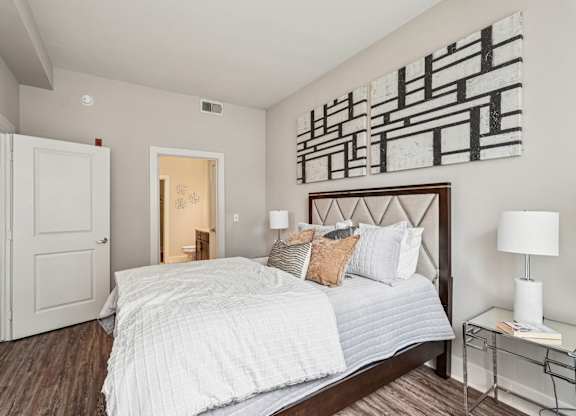 A bedroom with a large bed and a painting on the wall.