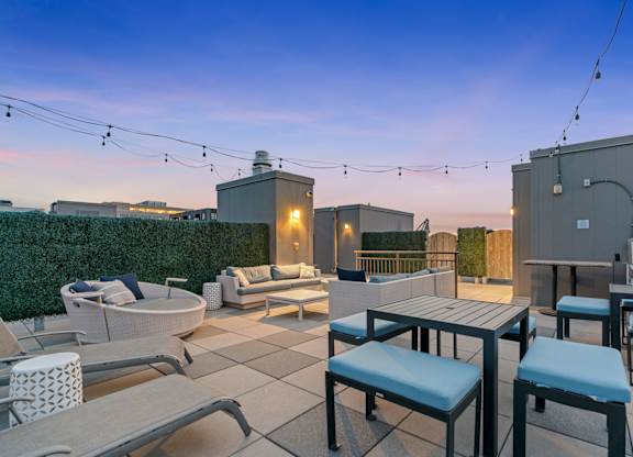 a rooftop patio with tables and chairs and a fire pit