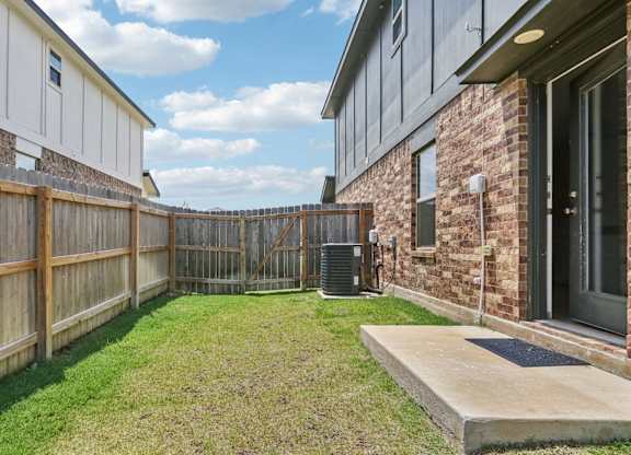 A backyard with a wooden fence and a brick building.