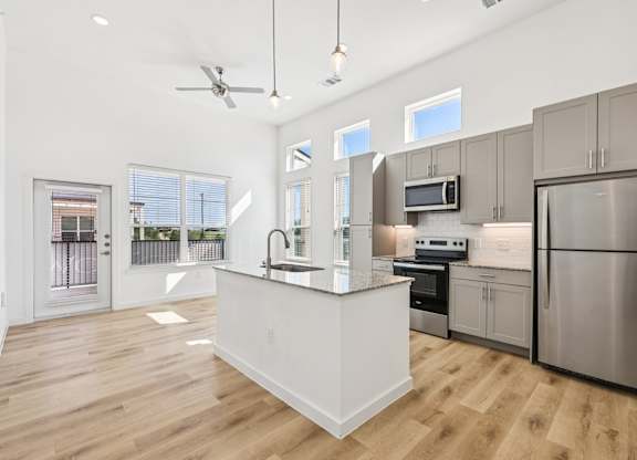 A modern kitchen with stainless steel appliances and wooden floors.