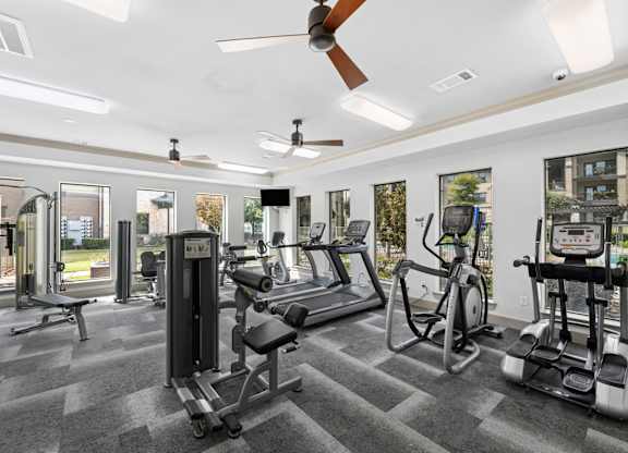 A gym with a variety of equipment including a treadmill, weights, and a stationary bike.