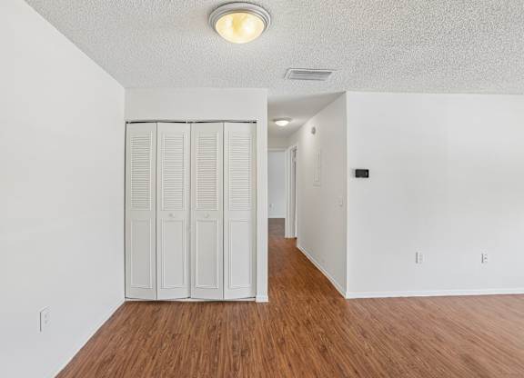 Closet with white doors in a room with wood floors.