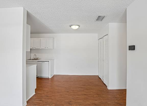 A kitchen with white cabinets and a wooden floor.